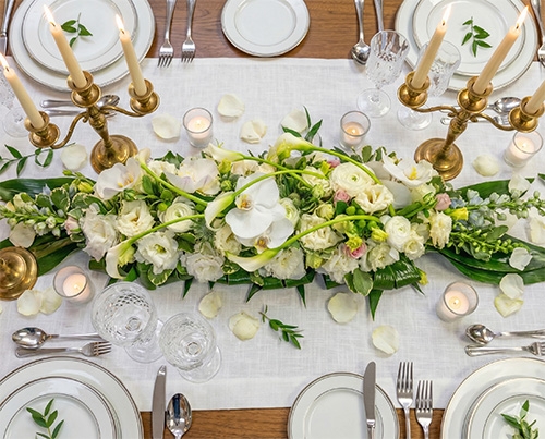 Centre de table floral blanc avec bougies, par la fleuristerie Tournesols au salon du mariage de Charleroi.